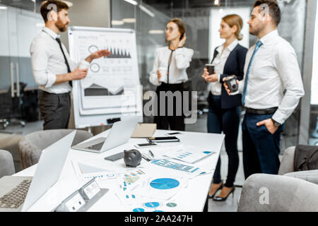Business people during a conference in the meeting room, image focused on the table with charts and gadgets Stock Photo