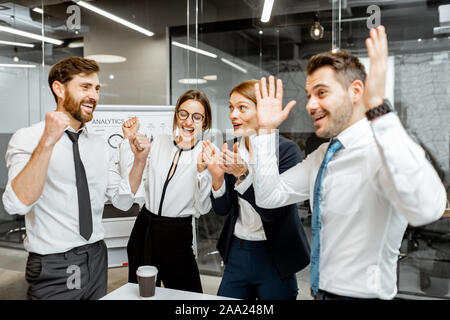 Successful company employees feeling excited with a good financial performance, hard working together in the meeting room Stock Photo