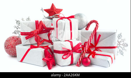 Heap of similar Christmas silver gift boxes with red ribbon decor stars baubles and candy cane isolated on white background Stock Photo
