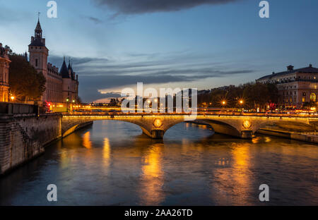 Stone bridge Pont au Change in Paris at the dusk. On the left are towers of Conciergerie, on right northern bank of river Seine Stock Photo