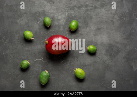 Tropical fruit feijoa and mango on dark concrete background with copy space for text. Flat lay. Healthy organic food concept. Stock Photo