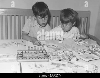 Hobby in the 1950s. Two boys is sitting at a table with their collection of stamps. It looks as if the many different postal stamps are being sorted and categorized. Sweden 1950s Stock Photo