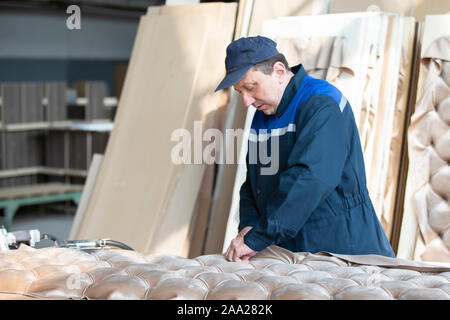 Belarus, the city of Gomil on April 29, 2019. Wood processing plant.Worker in the workshop for the production of beds. The master makes luxury furnitu Stock Photo