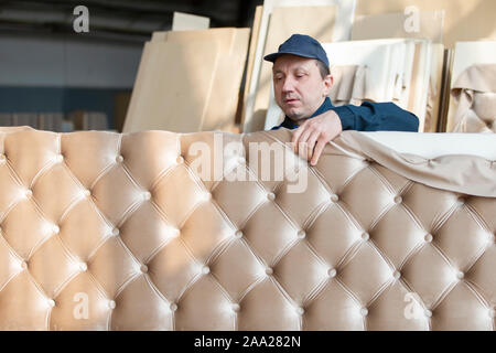 Belarus, the city of Gomil on April 29, 2019. Wood processing plant.Worker in the workshop for the production of beds. The master makes luxury furnitu Stock Photo