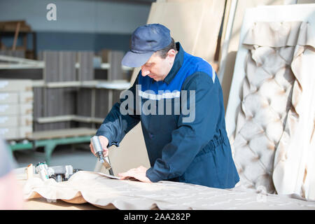 Belarus, the city of Gomil on April 29, 2019. Wood processing plant.Worker in the workshop for the production of beds. The master makes luxury furnitu Stock Photo