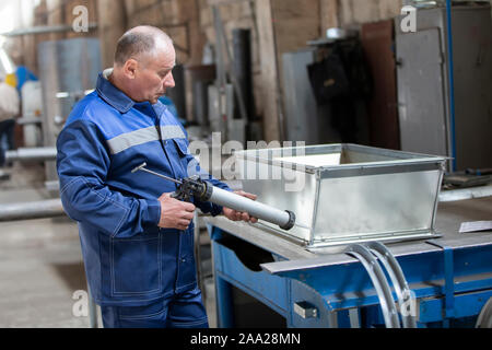 Belarus, Gomel, 25 April 2018. Factory for the manufacture of ventilation pipes.The worker at the factory makes ventilating metal pipes Stock Photo