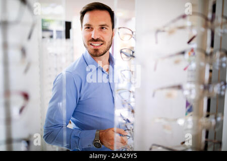 Health care, eyesight and vision concept - happy man choosing glasses at optics store Stock Photo