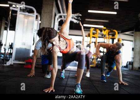 Healthy young people doing exercises at fitness studio. Stock Photo