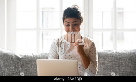 Happy indian woman reading email with great news on computer. Stock Photo