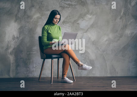 Turned full length body size photo of woman developing strategy for startup in orange pants white footwear near empty space on laptop isolated wall Stock Photo
