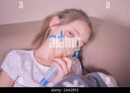 The little girl does inhalation at home.The girl sits with inhalation. The child is sick and sad. The little girl feels bad. Stock Photo