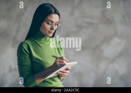 Photo of serious confident woman noting down information heard from employee holding copybook writing with pen isolated concrete grey color background Stock Photo