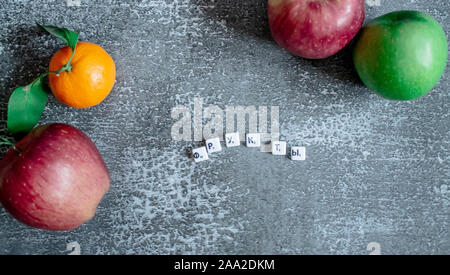 Gray background, oranges with leaves, red and greener apples from the top view from the top. The inscription fruits in Russian. Stock Photo
