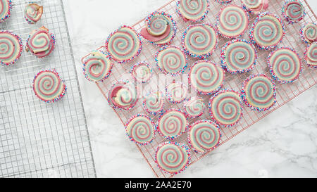 Step by step. Flat lay. Cooling freshly baked bake red, white, and blue pinwheel sugar cookies on a cooling rack. Stock Photo