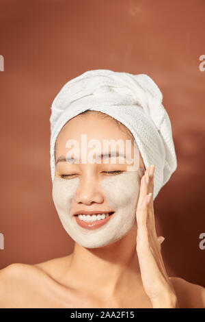Attracitve young Asian woman applying clay mask on her facee. Spa and wellness, skin care product concept. Stock Photo