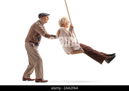 Full length profile shot of a senior man pushing his wife on a swing isolated on white background Stock Photo