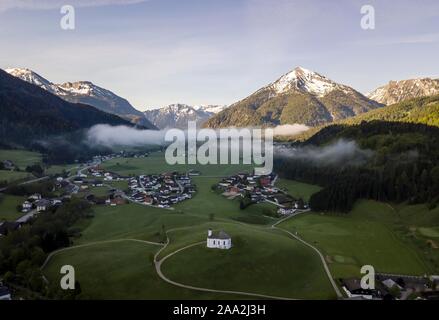 Aerial view, church Sankt Anna and village with early fog in front of Rofan Mountains, Achenkirch, Tyrol, Austria Stock Photo