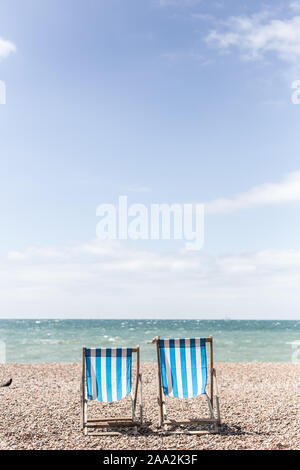Bird standing next to two deckchairs on the beach, Brighton, East Sussex, England, United Kingdom Stock Photo