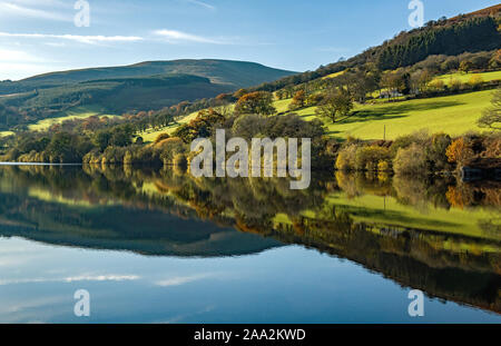 Reflections of the hills and trees surrounding Talybont Reservoir in the Brecon Beacons National Park Powys, south Wales. Autumn has arrived. Stock Photo