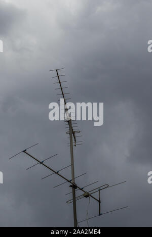 An antenna on top of a building stands isolated against a sky with stormy clouds image with copy space in vertical format Stock Photo