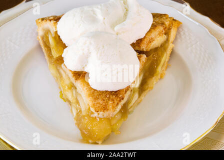 slice of homemade apple pie with two scoops of vanilla ice cream on top making it A la mode style. Served on antique china plates. Stock Photo