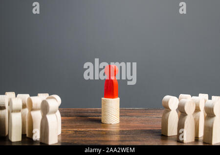 A people crowd looks at a red man. Cooperation and collaboration. Leader and leadership skills, management. An idol to follow. Fundraising and gather Stock Photo