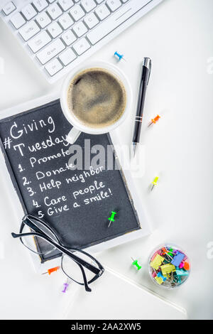 Chalk board with list of tasks, ideas, task for Giving Tuesday. Notes to various helping on Tuesday. International Charity Aid Day concept. White desk Stock Photo