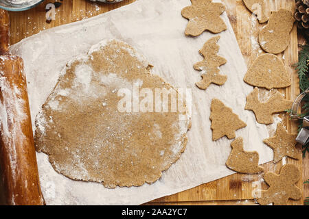 Making christmas gingerbread cookies, flat lay. Raw dough in shape of man,christmas tree, star, deer and wooden rolling pin, anise, ginger, cinnamon, Stock Photo