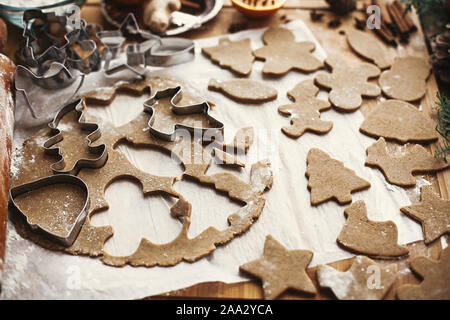 Gingerbread dough with metal cutters in different shapes for christmas cookies and wooden rolling pin, anise, ginger, cinnamon, pine cones, fir branch Stock Photo