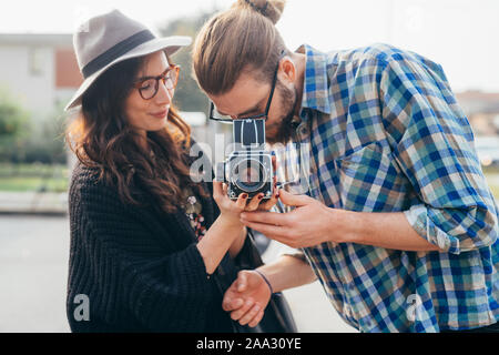 Young beautiful happy couple outdoor using old camera - activities, free time, togetherness concept Stock Photo
