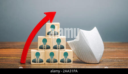 Wooden blocks with the image of a team of workers and a shield with up arrow. Working staff insurance concept. Employee protection. Increase security Stock Photo