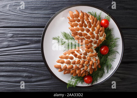 Winter salad cheese appetizer with almonds in the form of pine cones close-up on a plate on the table. Horizontal top view from above Stock Photo