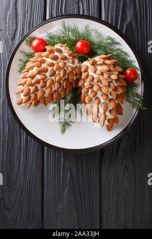 Christmas appetizer cheese salad with almonds in the form of cones close-up on a plate on the table. Vertical top view from above Stock Photo
