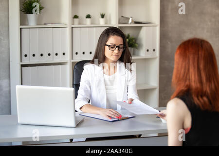 The dark-haired businesswoman reads CV of candidate at new job in her company. Selective focus. Stock Photo