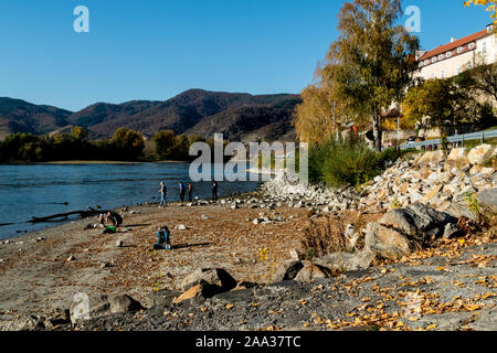 People on the riverside enjoying a breathtaking view over the river Danube at Durnstein, with the mountains in the background Stock Photo