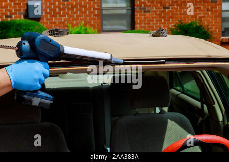 Glazier using silicone tools repairing automobile windshield replacement on a car Stock Photo