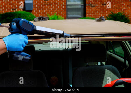Automobile windshield replacement man using silicone tools to fix special workers replacing windshield Stock Photo