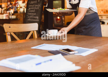 Waiter removing dirty dishes from the tables in restaurant. Stock Photo