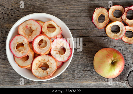 Dehydrated apples chips in wooden bowl on a wooden table, top view Stock Photo