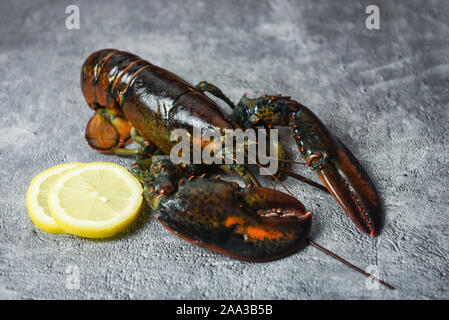 Fresh lobster shellfish in the seafood restaurant for cooked food / Raw lobster and lemon on a black stone table , selective focus Stock Photo