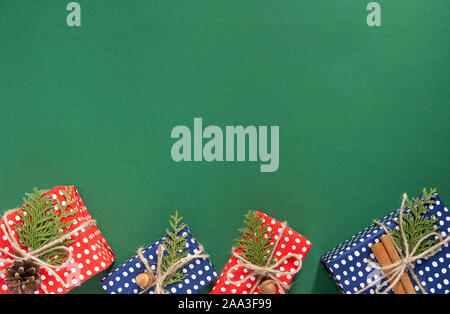 Red and blue gift boxes and thuja twigs with christmas tree cone and acorn on green background, merry christmas and happy new year concept, flat lay Stock Photo
