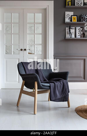 Nizhniy Novgorod, Russia - November 11, 2019: Photo studio 2.8. Armchair with black plaid laying on it stands in living room. Stock Photo