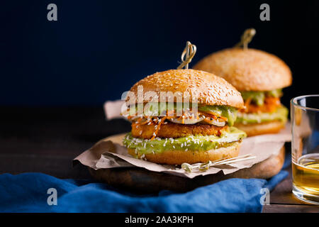 Vegan sweet potato chickpea burgers with avocado guacamole sauce and carrot slaw on dark blue background with copy space for text.Vegetarian meal Stock Photo