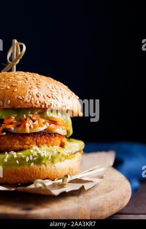 Vegan sweet potato chickpea burgers with avocado guacamole sauce and carrot slaw on dark blue background close-up with copy space for text.Vegetarian Stock Photo