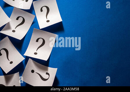 Printed question marks on white cards over blue Stock Photo