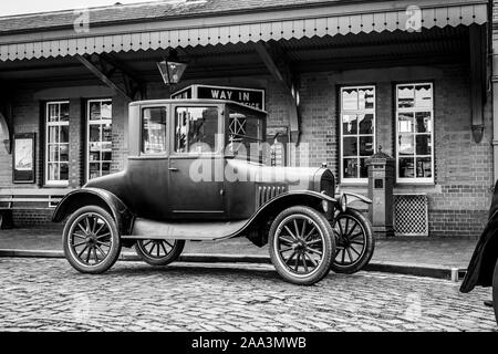 Black and white, side view close up of isolated vintage car: 1920s Ford Model T, parked outside vintage train station, Severn Valley heritage railway. Stock Photo