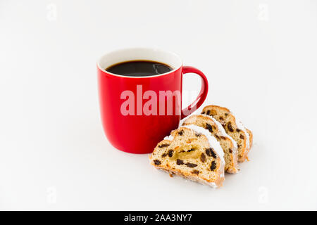 Stollen slices and red mug filled with black coffee isolated on white background. Angled view. Stock Photo
