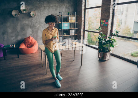 Full size photo of joyful afro american girl entrepreneur using cellphone reading social networking news chatting with colleagues in office loft Stock Photo