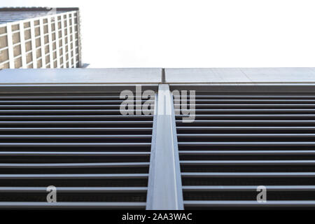 Tall building is shot from below. Blue sky and skyscraper and copy space. Horizontal and vertical lines as part of a multi-story building Stock Photo