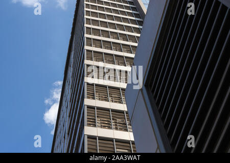 Tall building is shot from below. Blue sky and skyscraper and copy space. Horizontal and vertical lines as part of a multi-story building Stock Photo